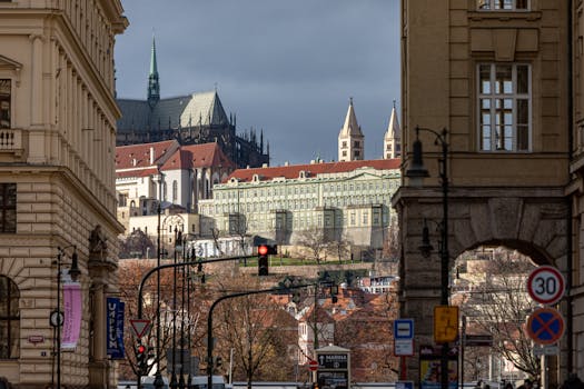 View of Prague cityscape featuring historical architecture and iconic cathedrals under a cloudy sky.