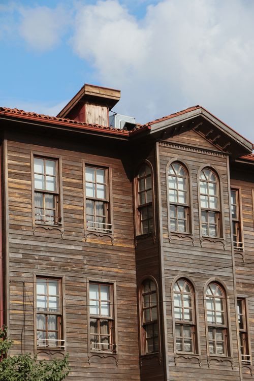 Free A classic rustic wooden building with intricate window designs against a bright blue sky. Stock Photo