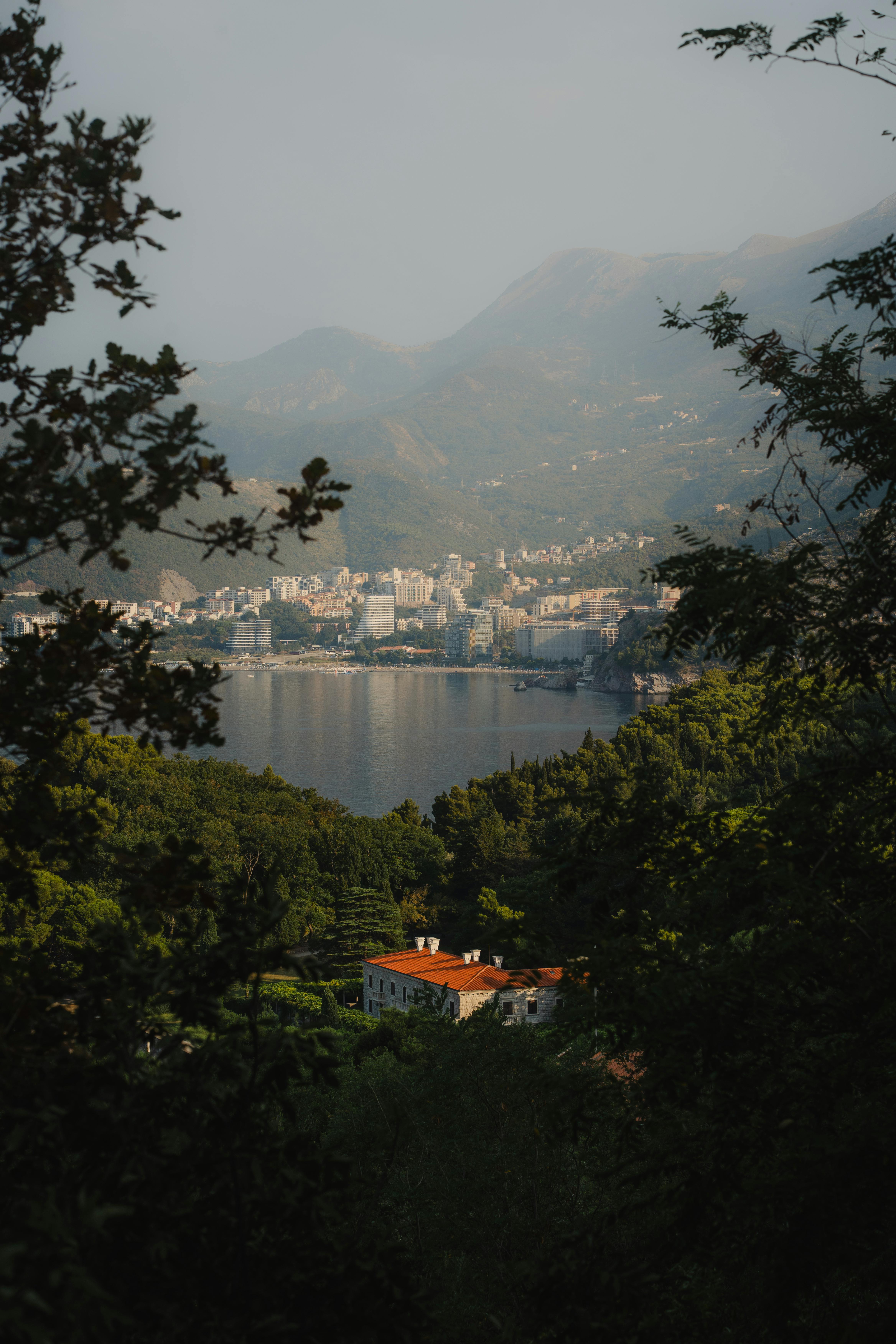 Explore the stunning landscape of Budva Bay with lush green mountains and city skyline.
