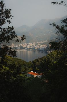 Explore the stunning landscape of Budva Bay with lush green mountains and city skyline.