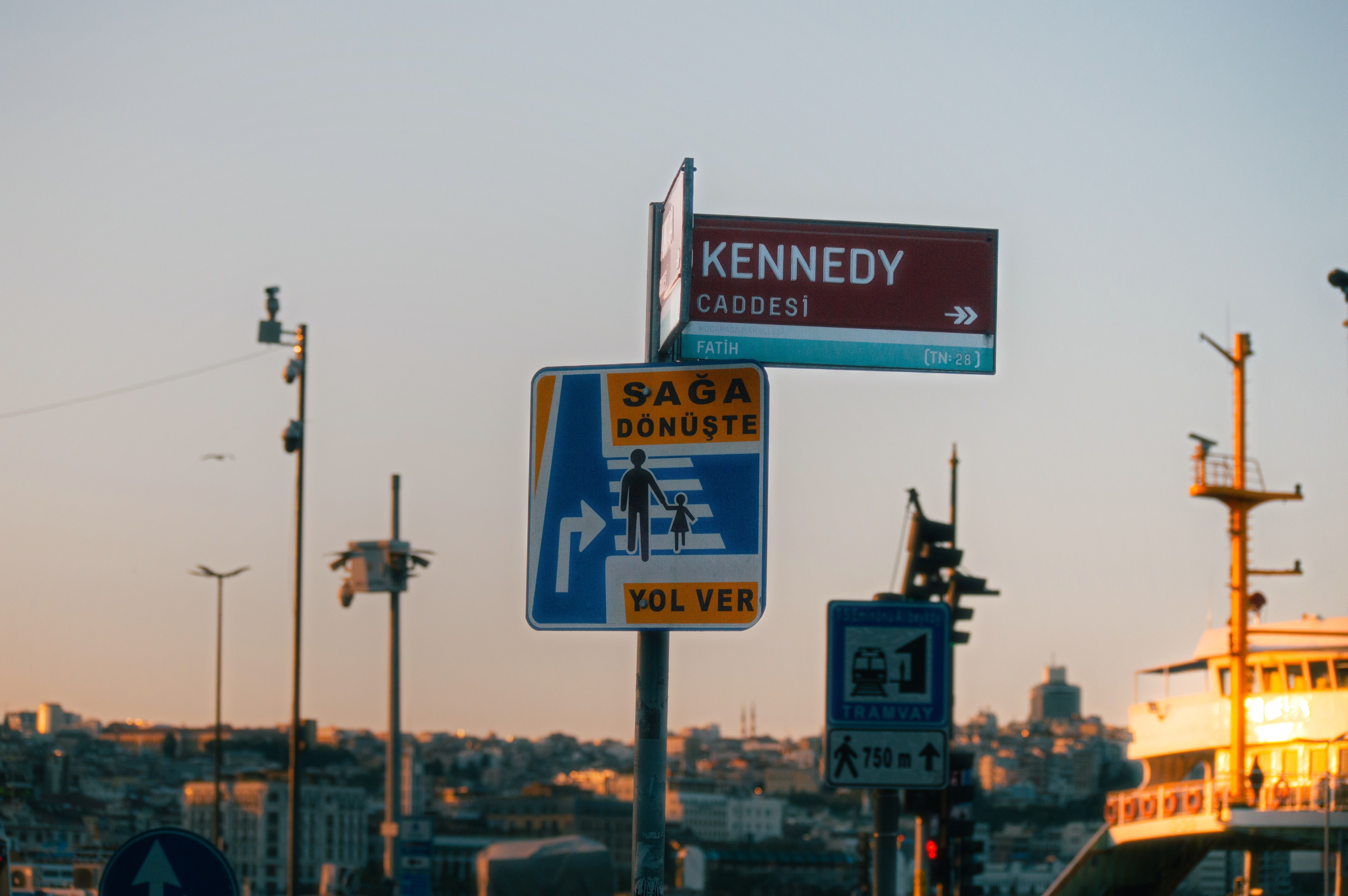 Street signs at Kennedy Avenue, Istanbul with sunset light reflecting on the cityscape.