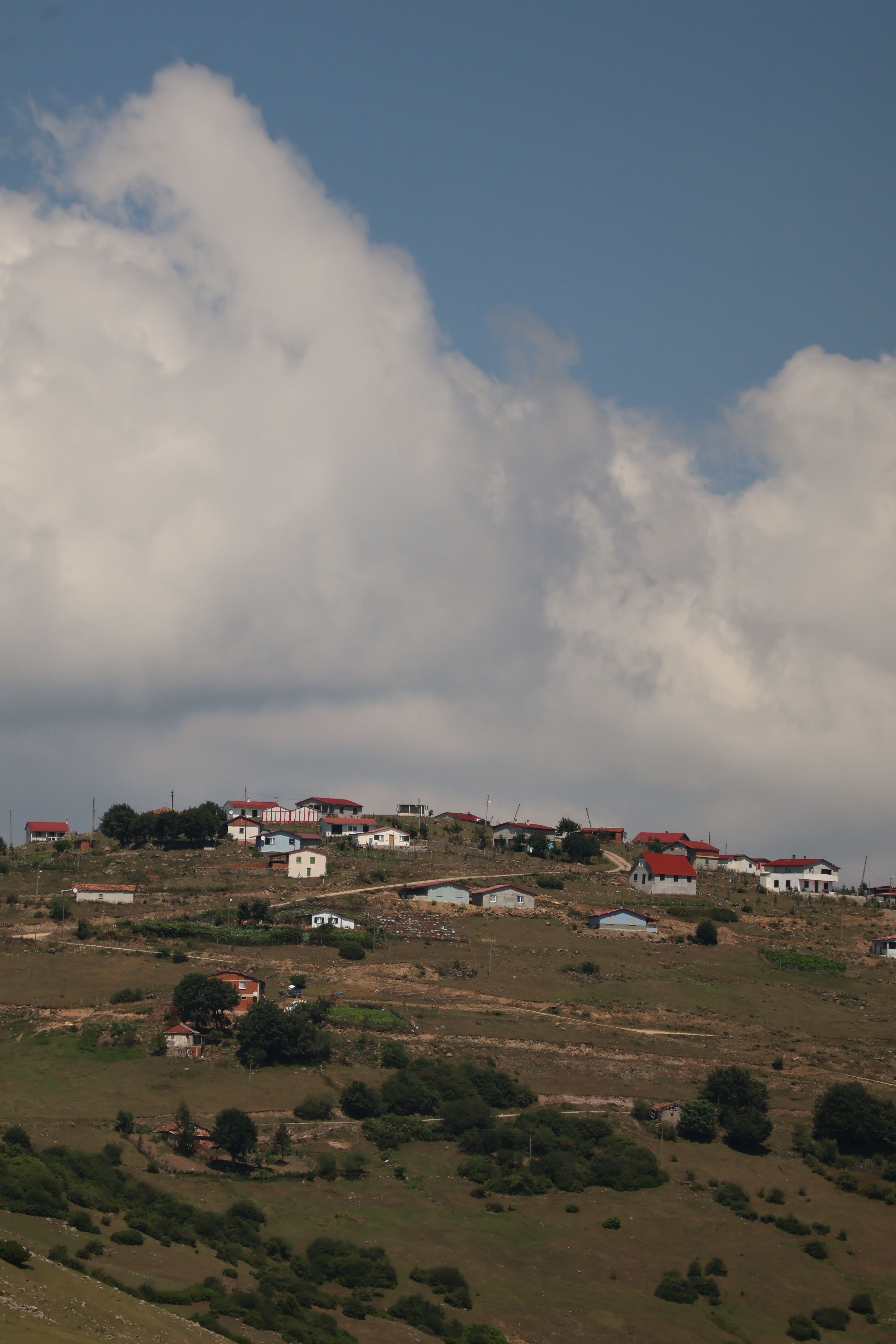 A picturesque village on a plateau with vibrant rooftops under a dramatic cloudy sky.