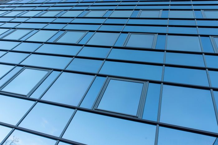 Gereinigte Glasfassade spiegelt den Himmel über München