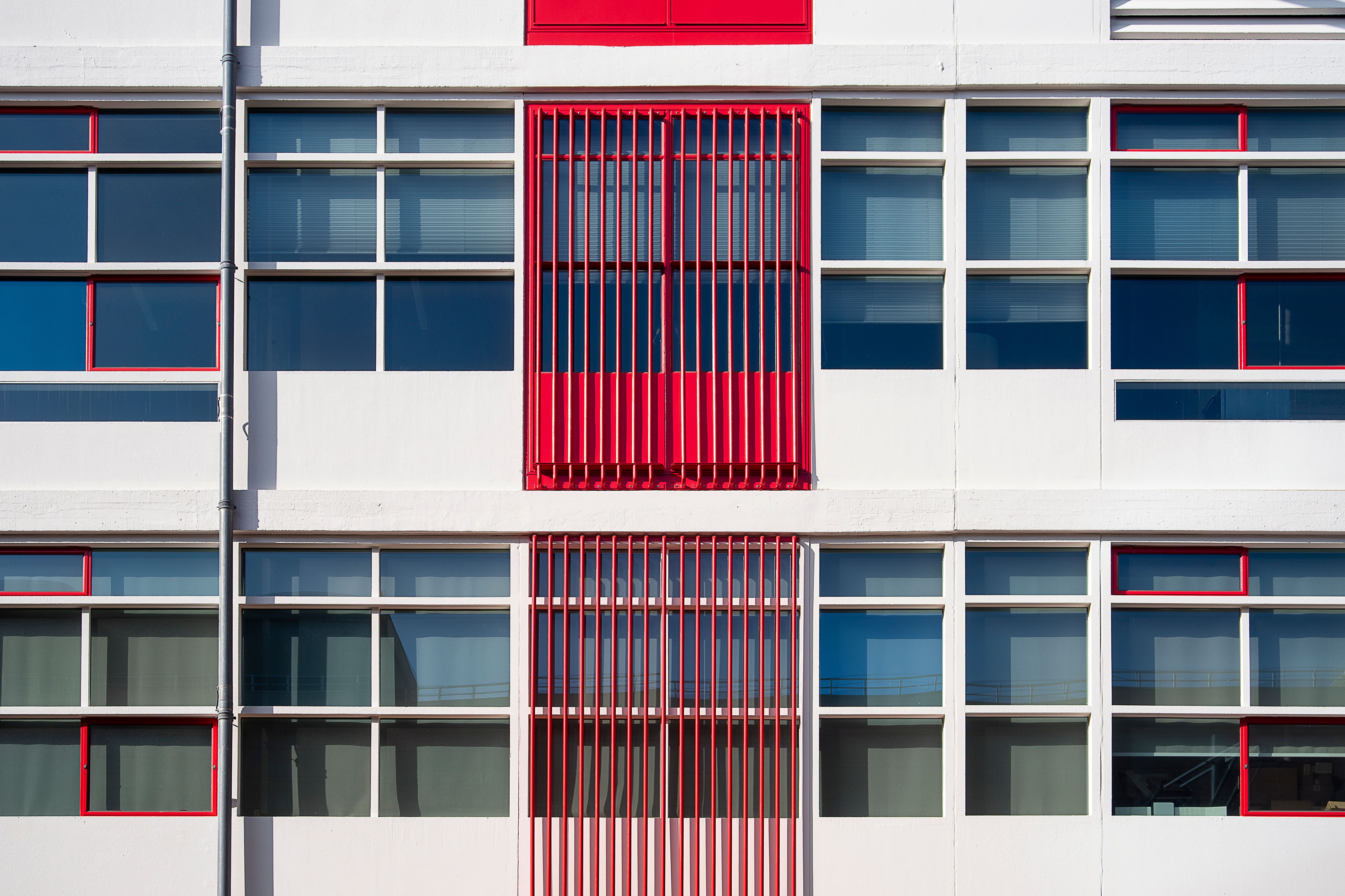 Abstract view of a modern building facade with red accents and grid windows.