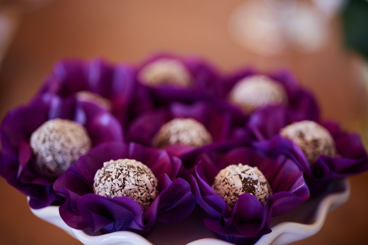 Delicious coconut truffles beautifully arranged in vibrant purple flower wrappers, perfect for parties.