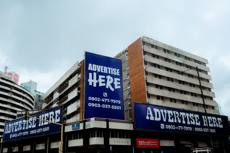 Large billboards on urban buildings displaying 'Advertise Here' in Lagos, Nigeria.