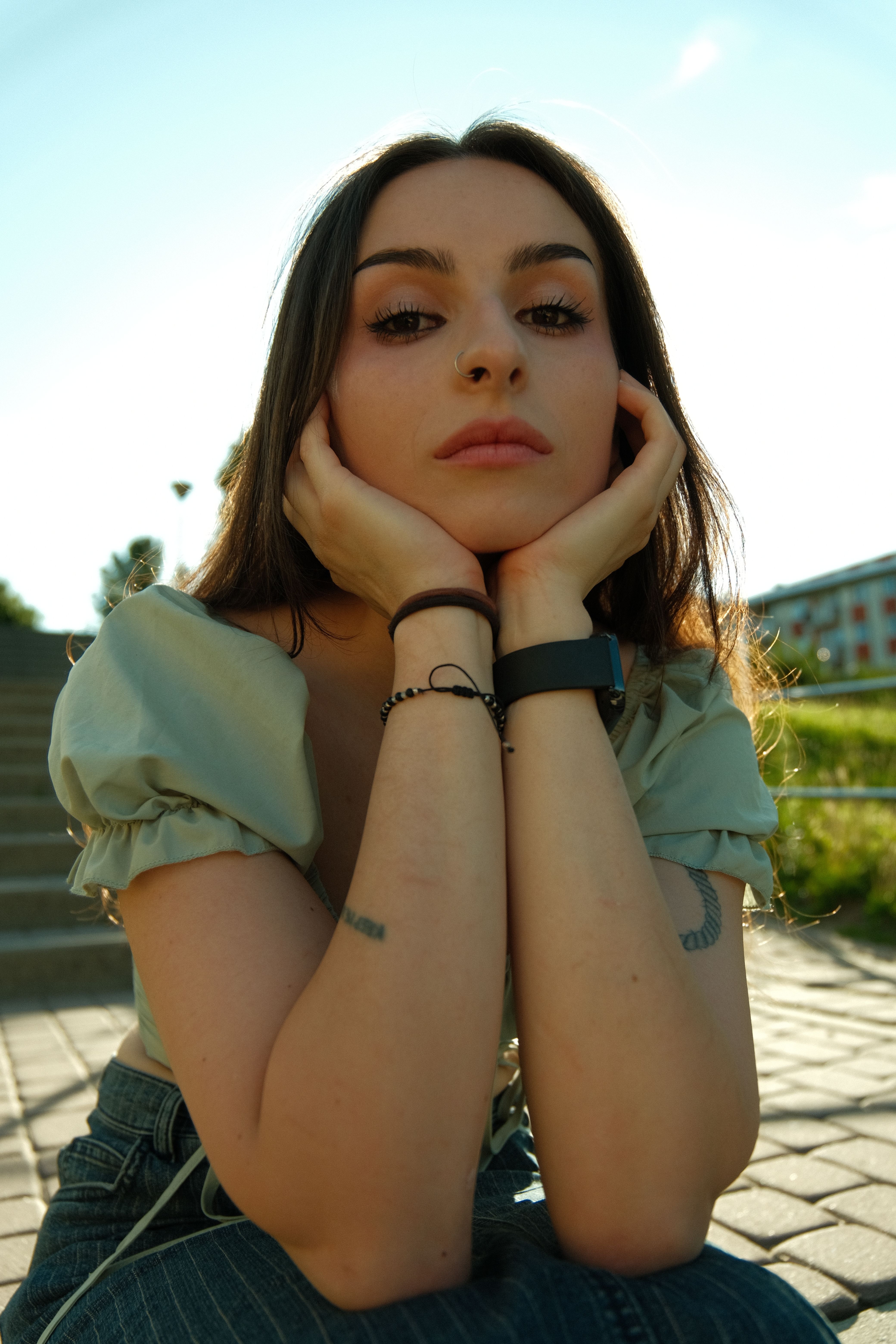 Portrait of a young woman sitting outdoors on a sunny day, relaxed and thoughtful.