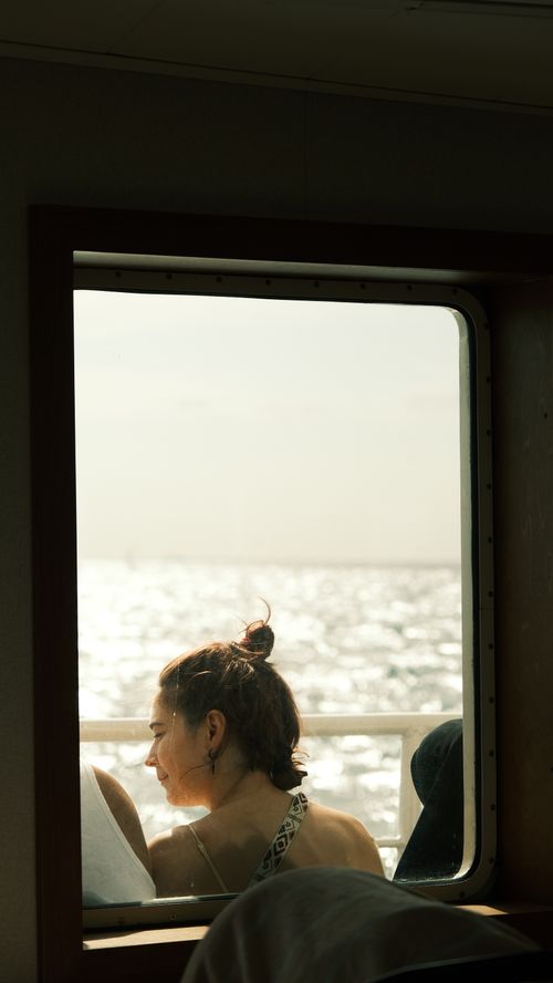 Free A woman looks out over the ocean through a ferry window, enjoying the tranquil view. Stock Photo