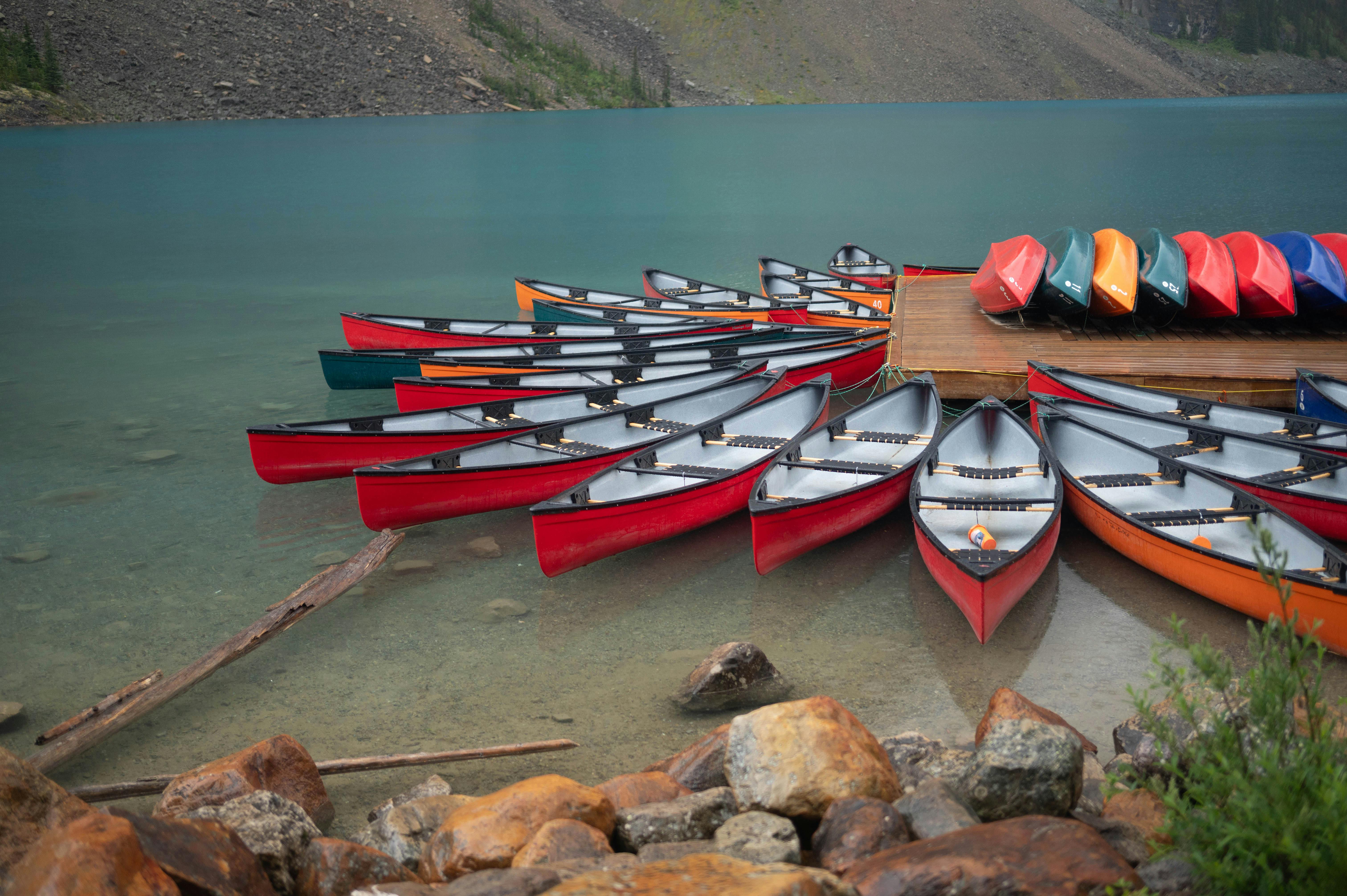 Vibrant canoes lined up on a serene lake in Canada, perfect for summer adventures.