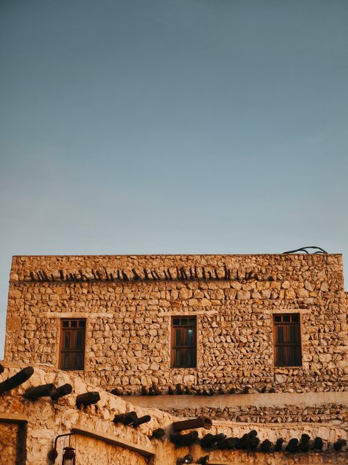 Free Capture of a historic stone building facade in Doha's Souq Waqif, Qatar, under a clear sky. Stock Photo