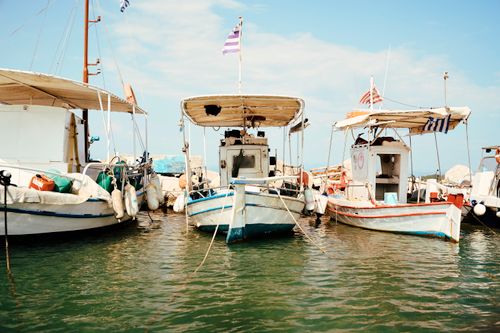 Free A scenic view of traditional fishing boats docked in Corfu, Greece under a clear blue sky. Stock Photo
