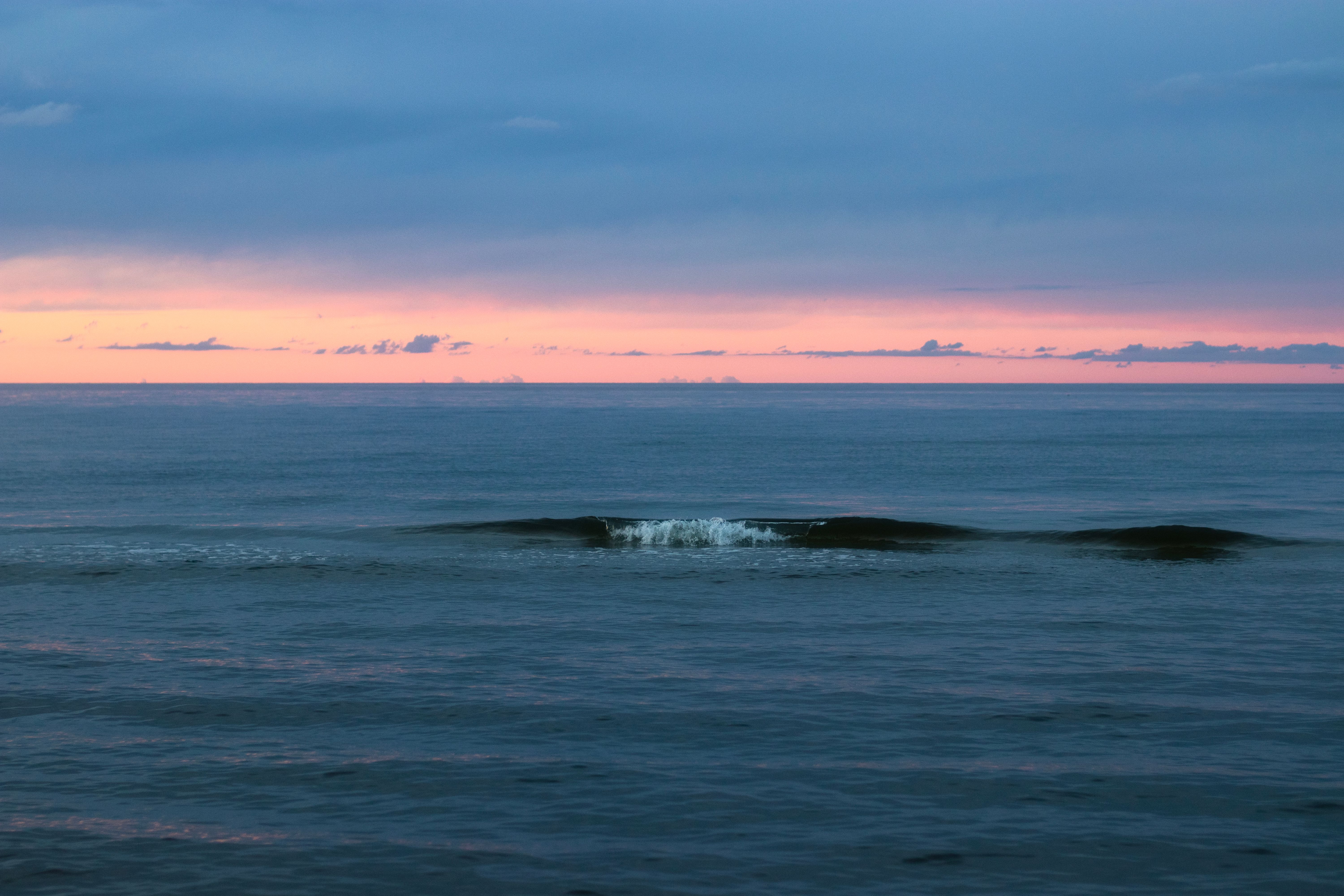 Soft waves rolling onto an empty beach at dusk with fading golden light