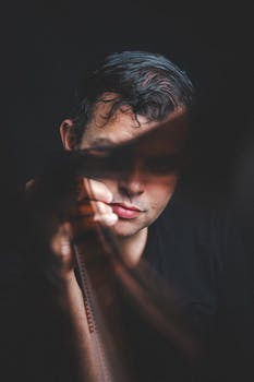 Dramatic portrait of a young man holding a film strip, captured in low light for a moody effect.