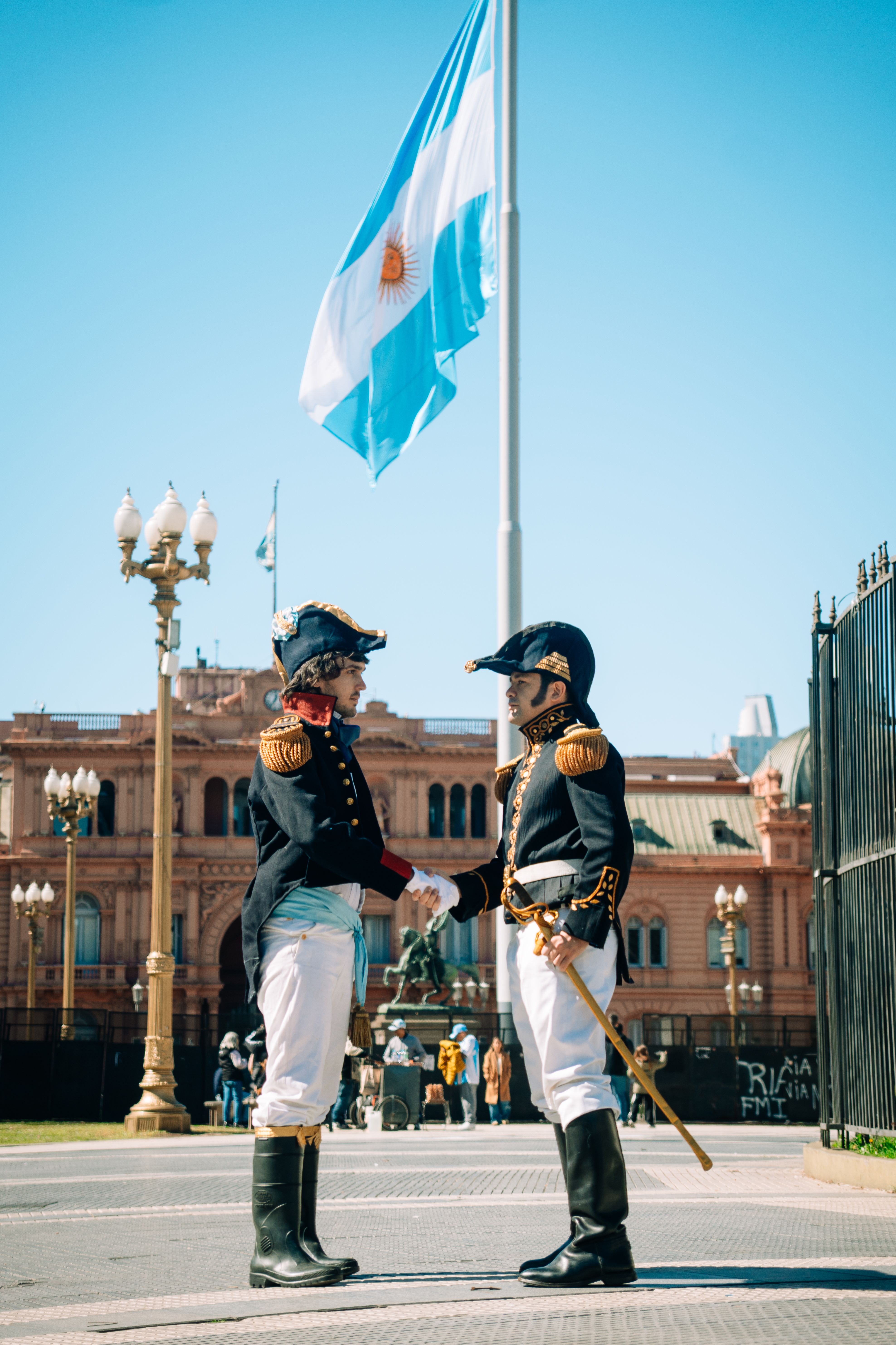 Historical reenactment of Argentinian soldiers in front of Casa Rosada with national flag in Buenos Aires.