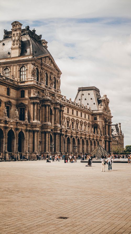 Free People explore the Louvre Museum in Paris, France, showcasing its grand architecture on a clear day. Stock Photo