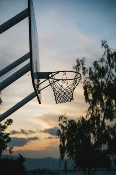 Silhouette of a basketball hoop against a vibrant sunset in Guatemala, capturing a peaceful moment.