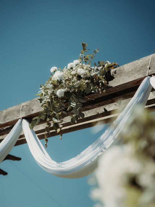 Free Beautiful wedding arch adorned with white flowers and drapery against a clear blue sky. Stock Photo
