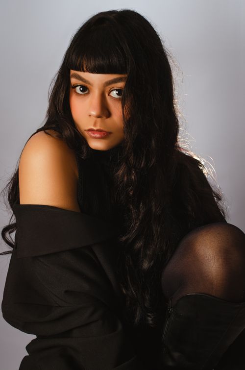 Free Elegant portrait of a woman with long dark hair, wearing a black outfit. Stock Photo