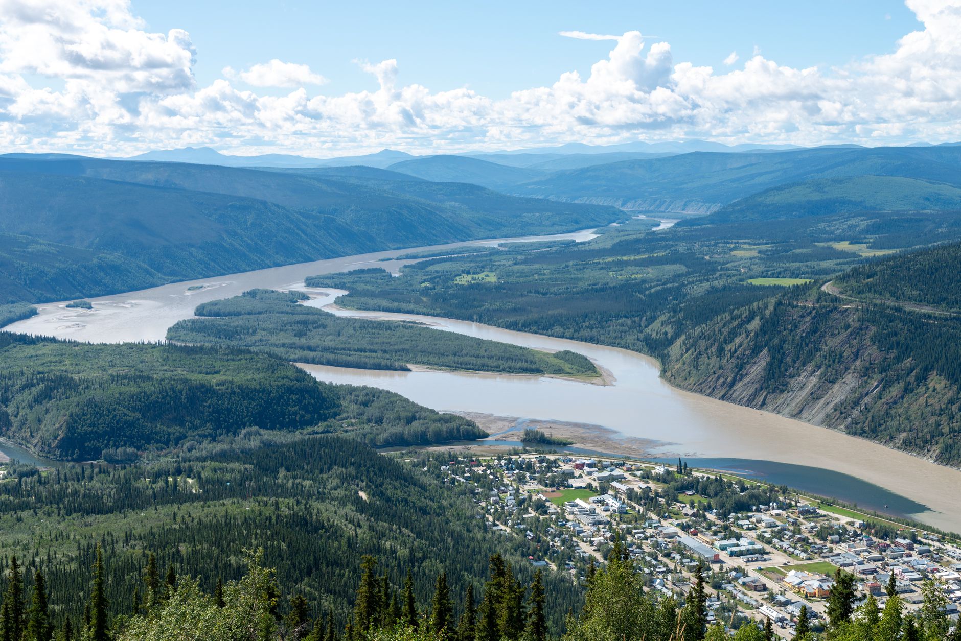 A breathtaking aerial shot of Dawson City, Yukon, Canada with the scenic Yukon River winding through lush green valleys.