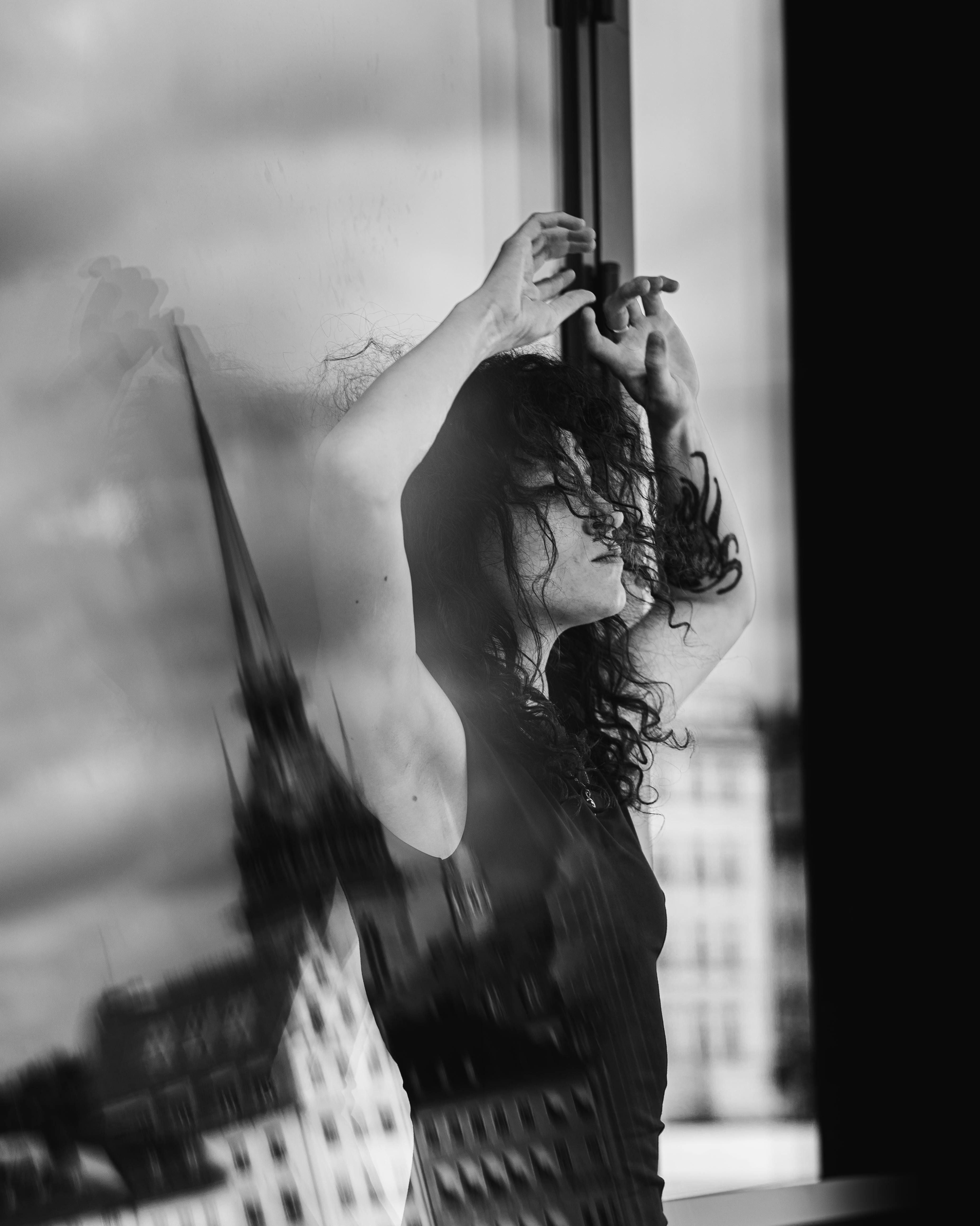 Moody black and white portrait with reflection in cityscape window.