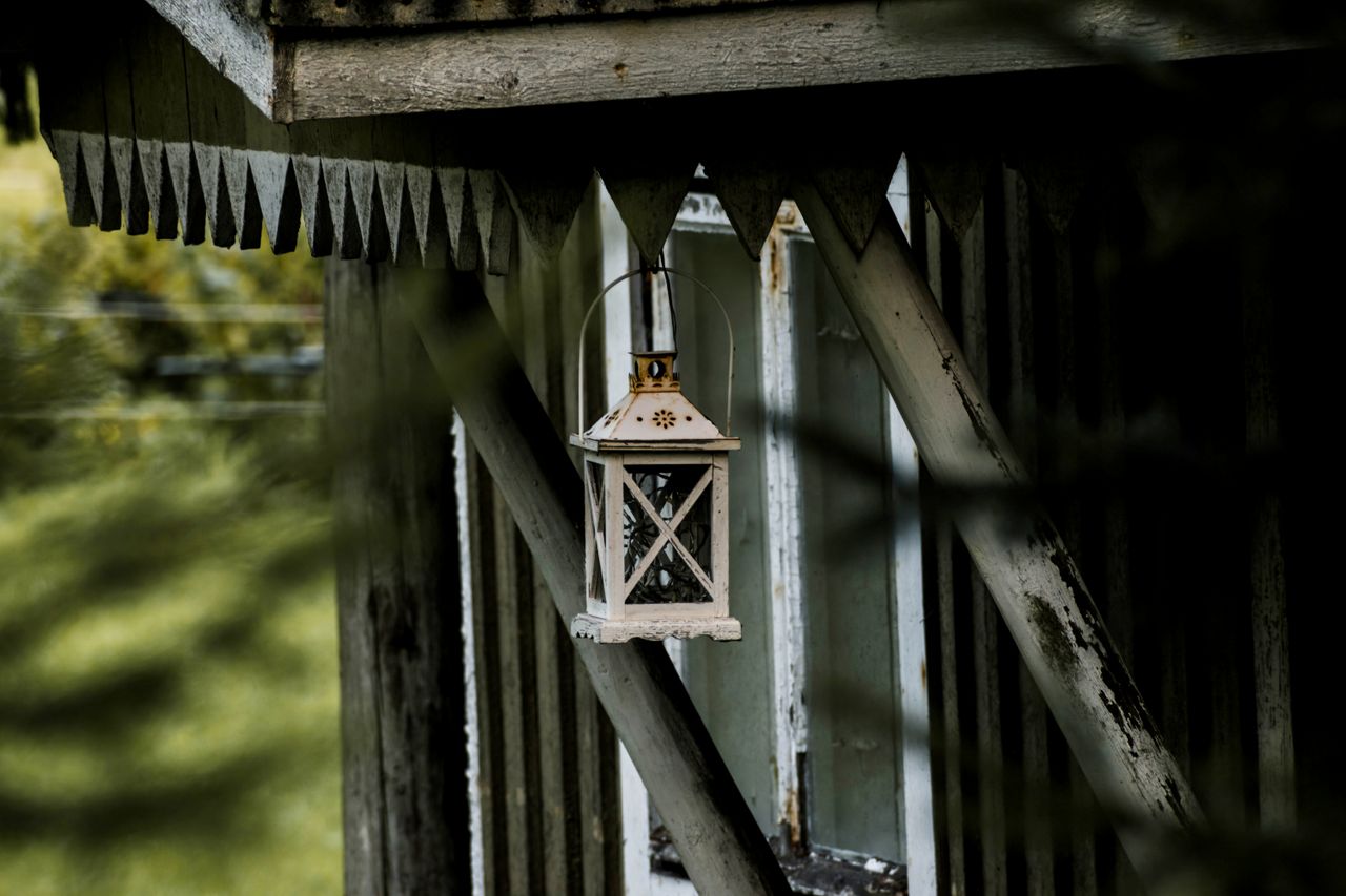 a vintage style lantern hangs from a weathered wooden structure evokin