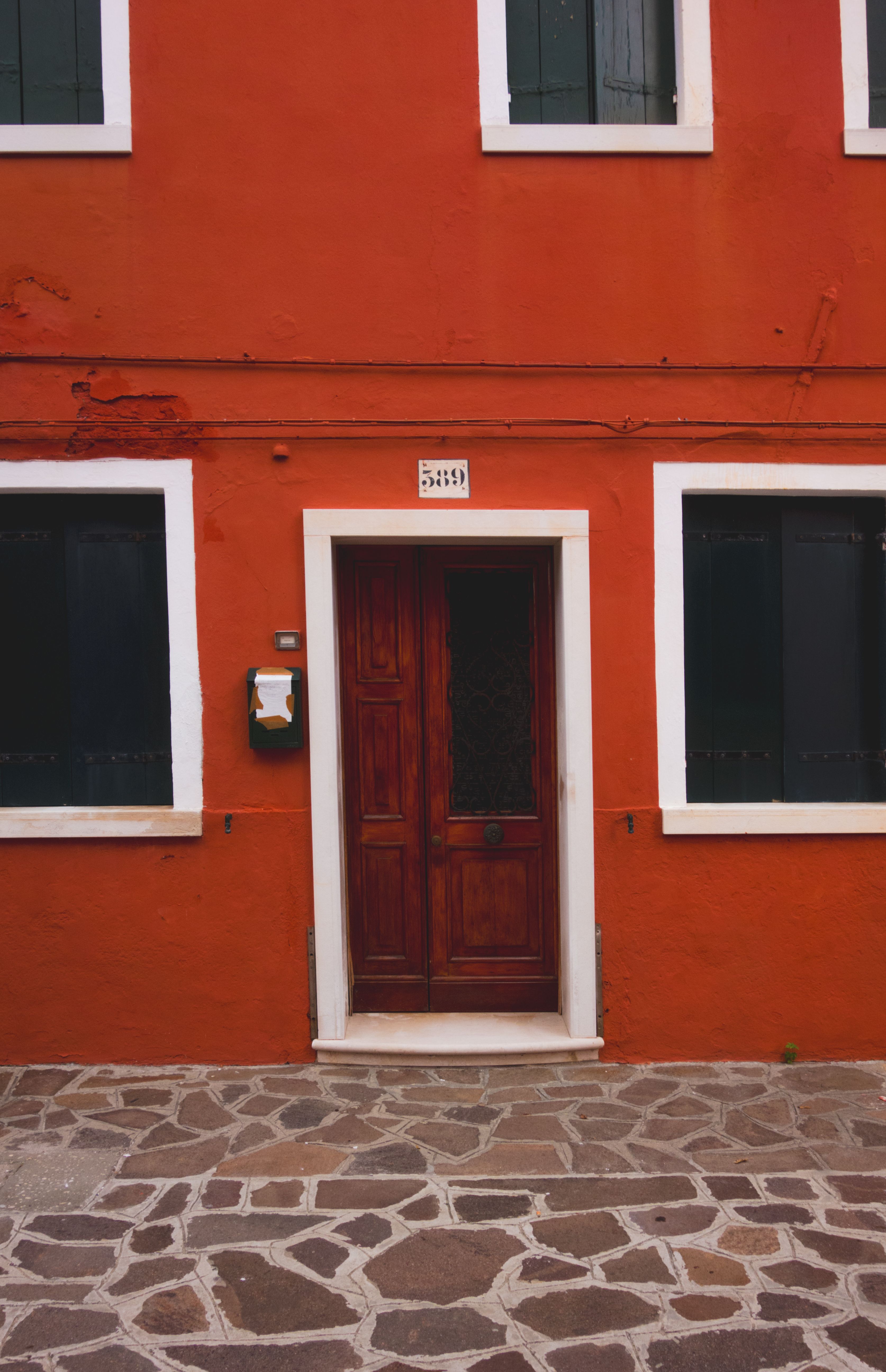 A rustic red facade with a wooden door and classic windows, showcasing Italian architectural style.