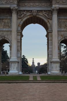 View of Sforza Castle through the Arch of Peace in Milan, Italy at sunset.