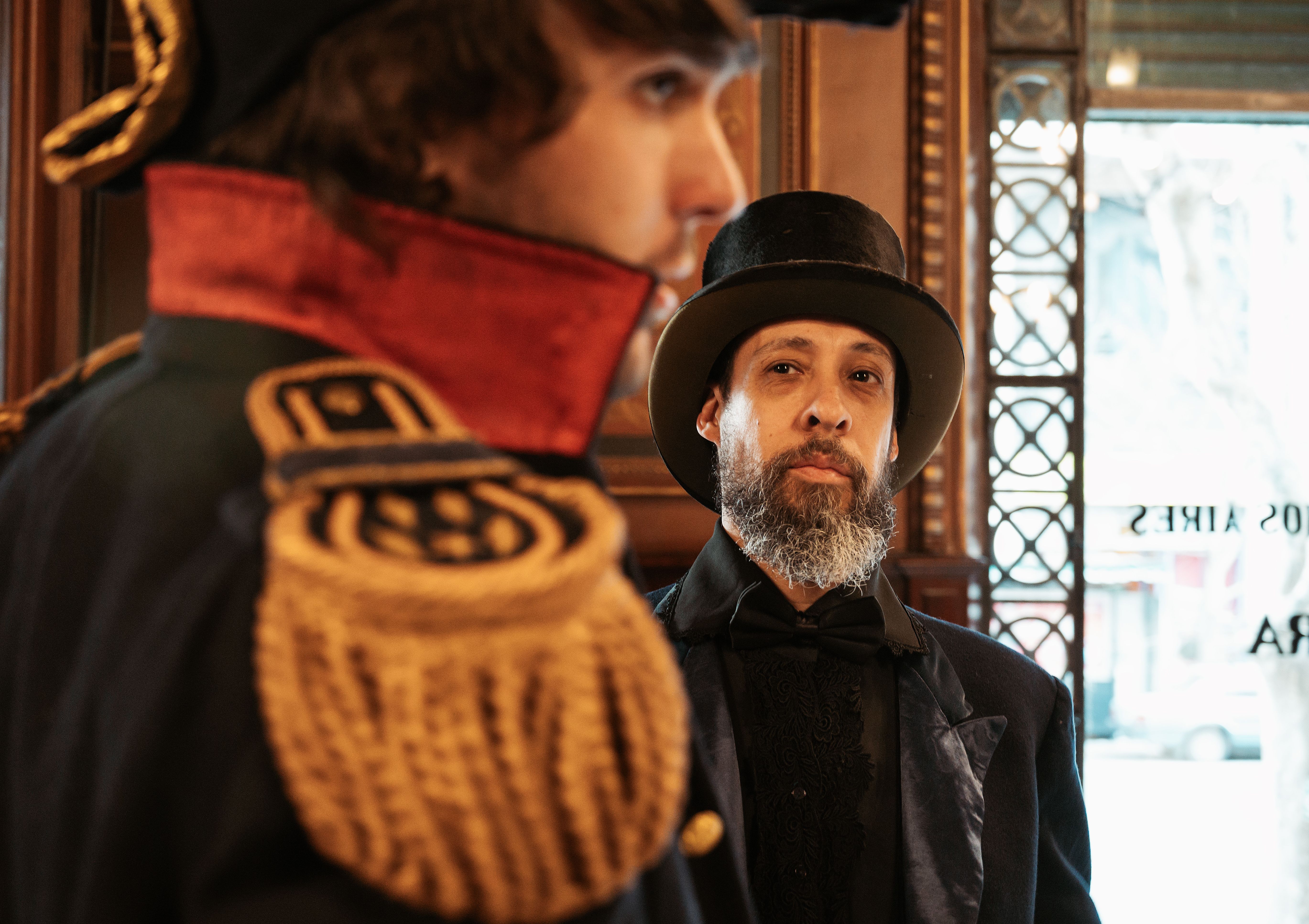 Two men in vintage attire inside a Buenos Aires cafe, evoking historical elegance.