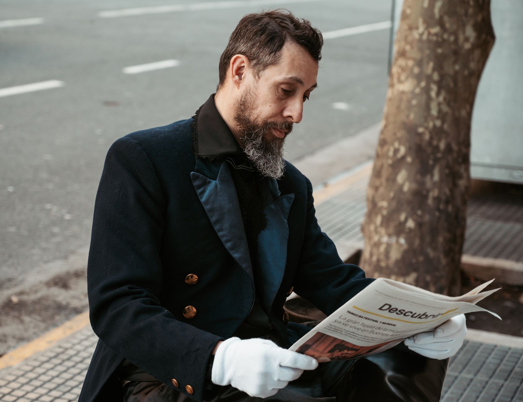 A man sits on a Buenos Aires street, deeply engaged with a newspaper, reflecting daily life in Argentina.