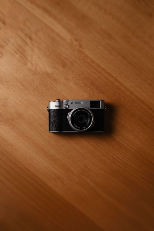 Free A classic camera placed on a warm wood texture, capturing a minimalist aesthetic. Stock Photo