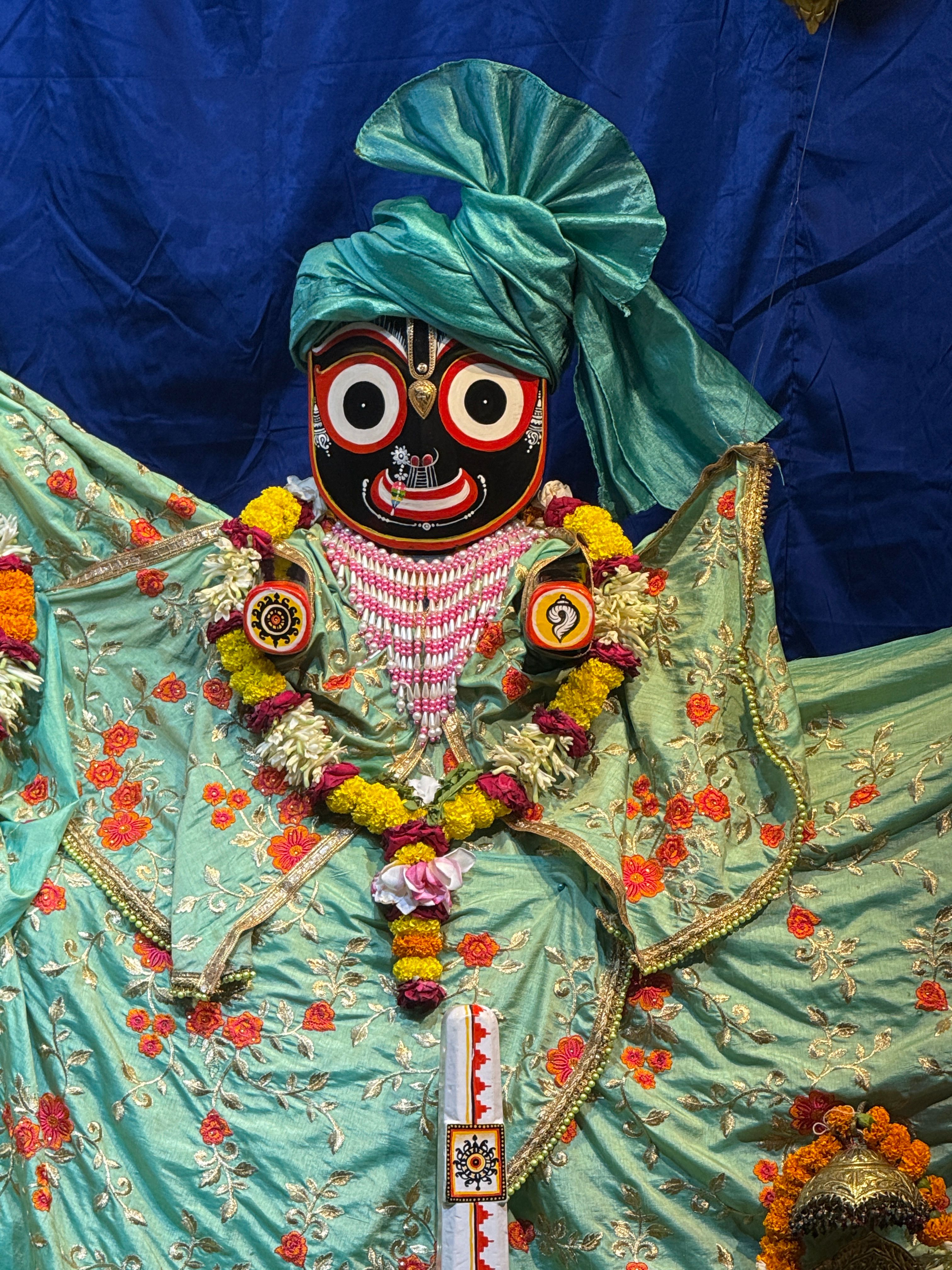 Vibrant statue of a traditional Indian deity adorned with colorful floral garlands