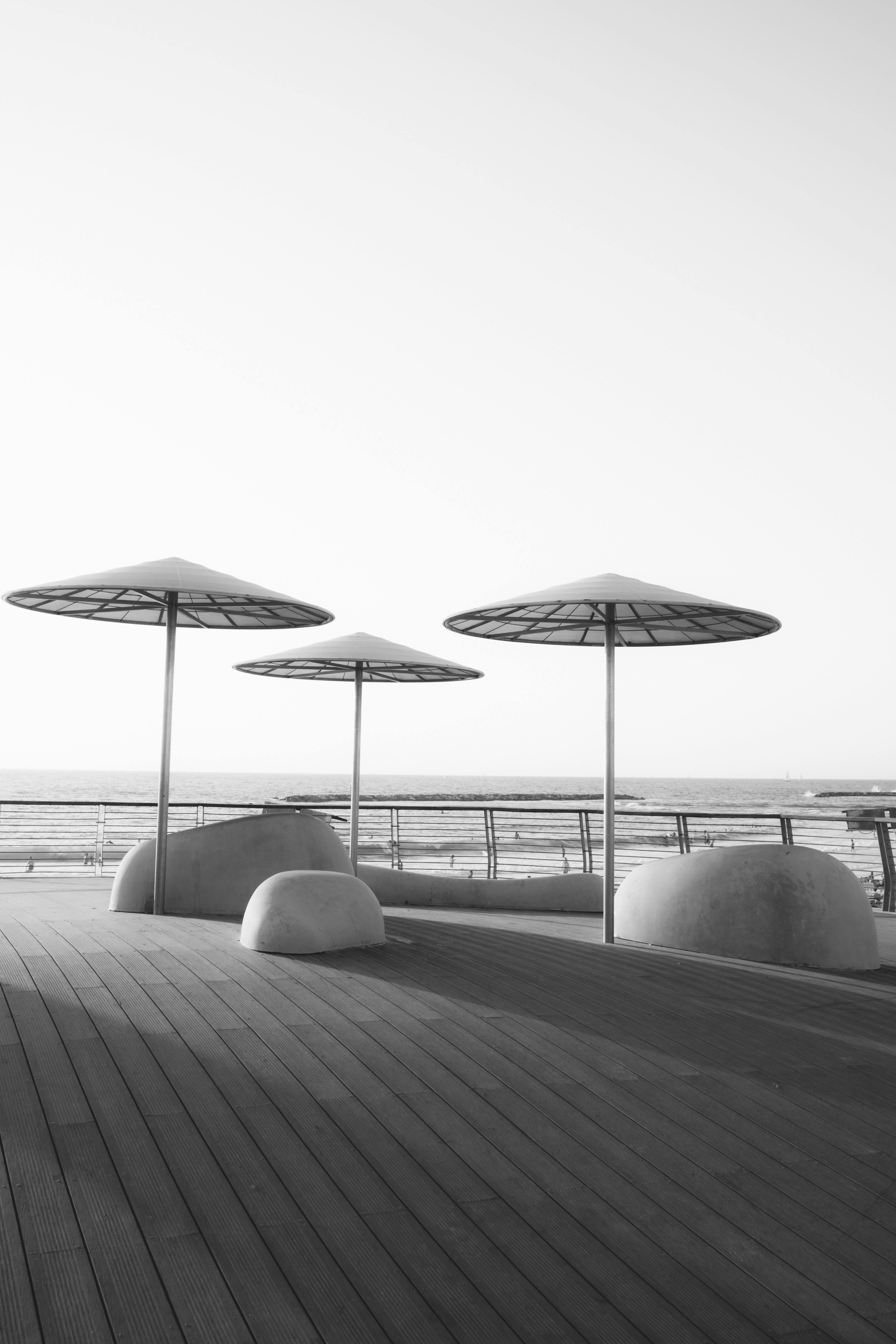 极简主义的沿海长廊，黑白色调，雨伞作为点缀