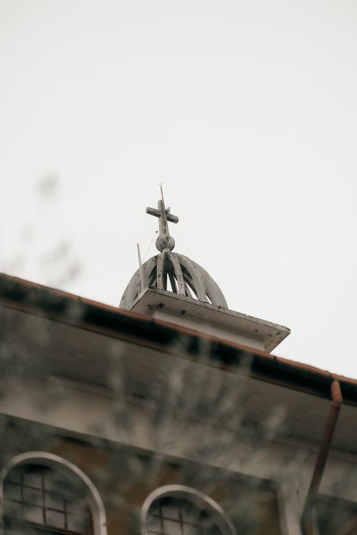 Free Close-up of a historic church steeple and cross against a cloudy sky, evoking a serene and timeless feel. Stock Photo