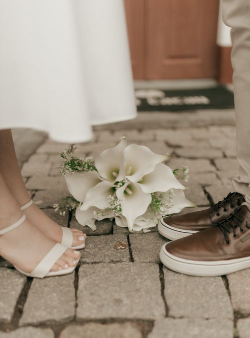 Free A close-up of wedding shoes and bouquet on cobblestones symbolizing romance. Stock Photo