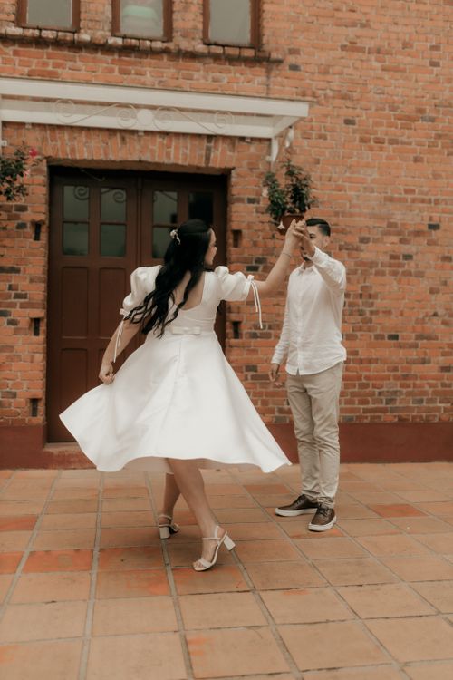 Free Happy couple dancing outdoors in front of a rustic brick building, capturing a moment of love and joy. Stock Photo