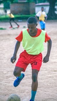 Young soccer player dribbles ball during practice on a dirt field.