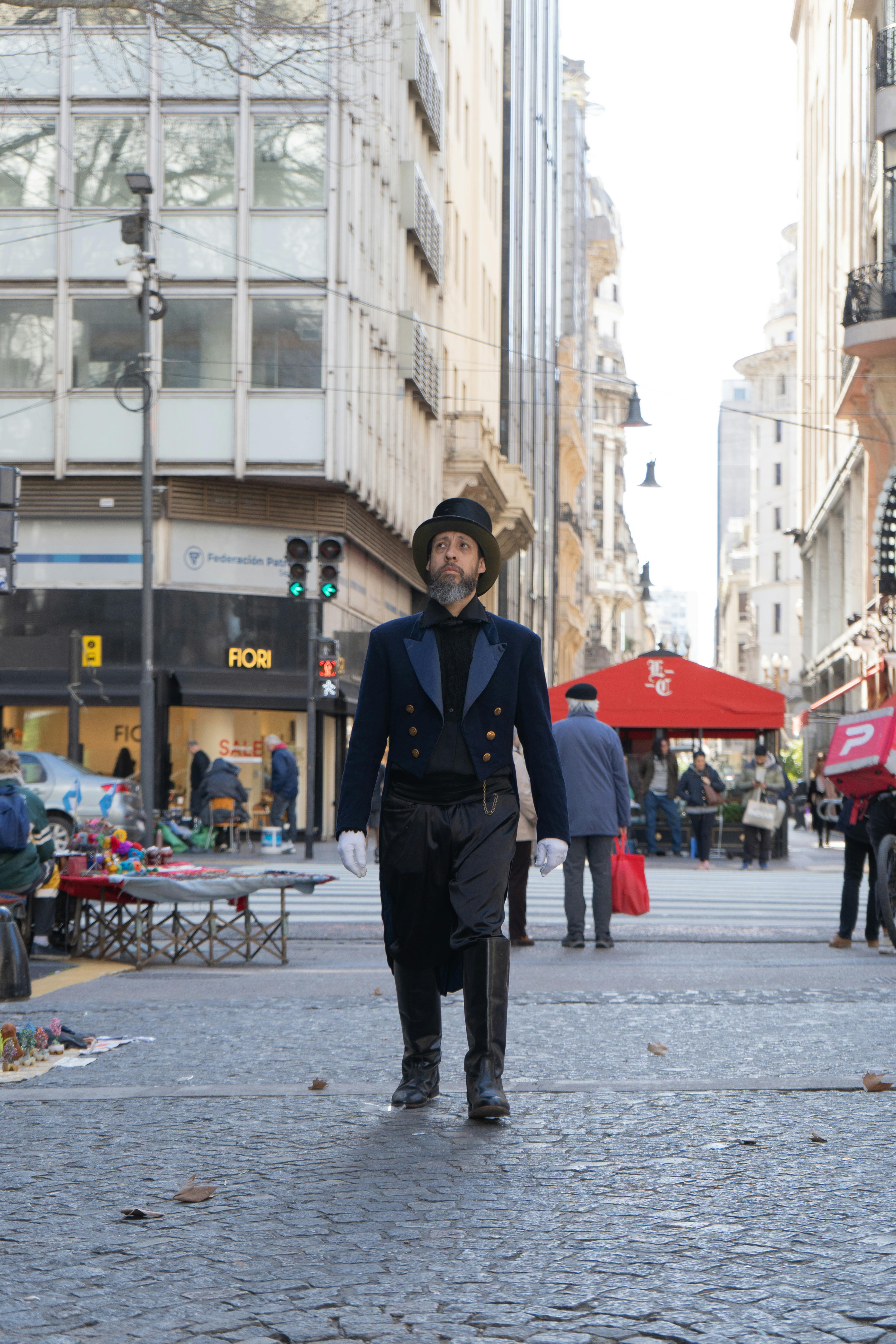 A gentleman in classic attire strolls through a lively city street with historic architecture.