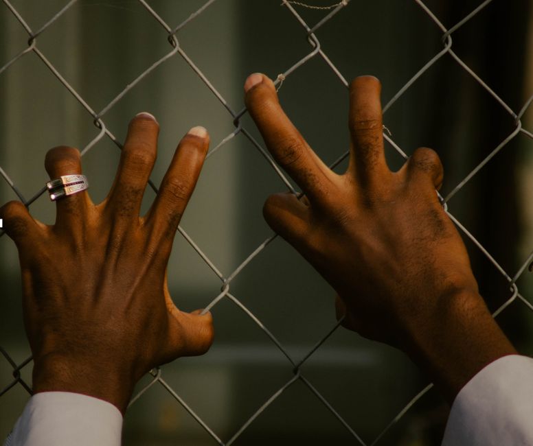Hands gripping a wire mesh fence