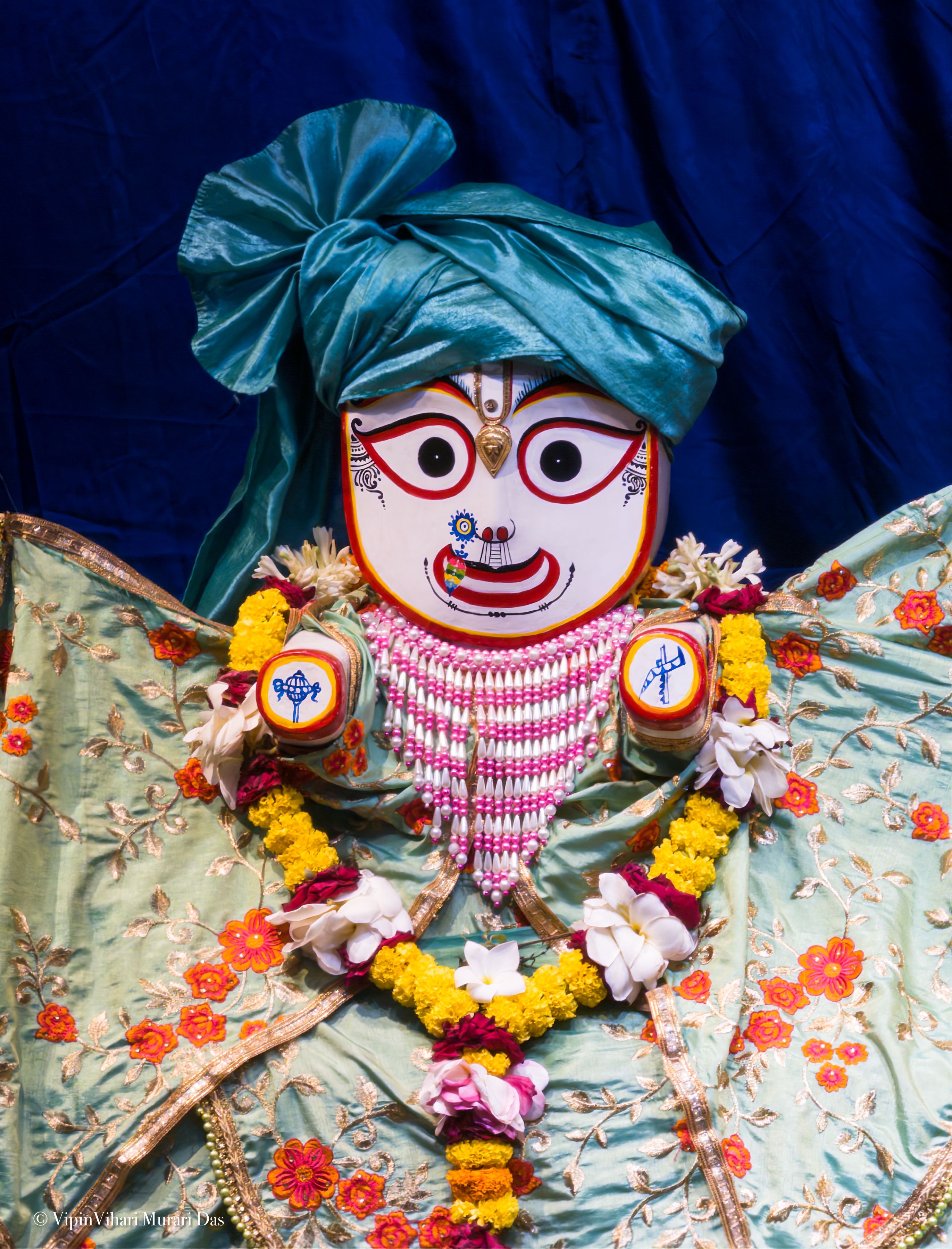Colorful Indian festival deity decoration with flowers and intricate attire.