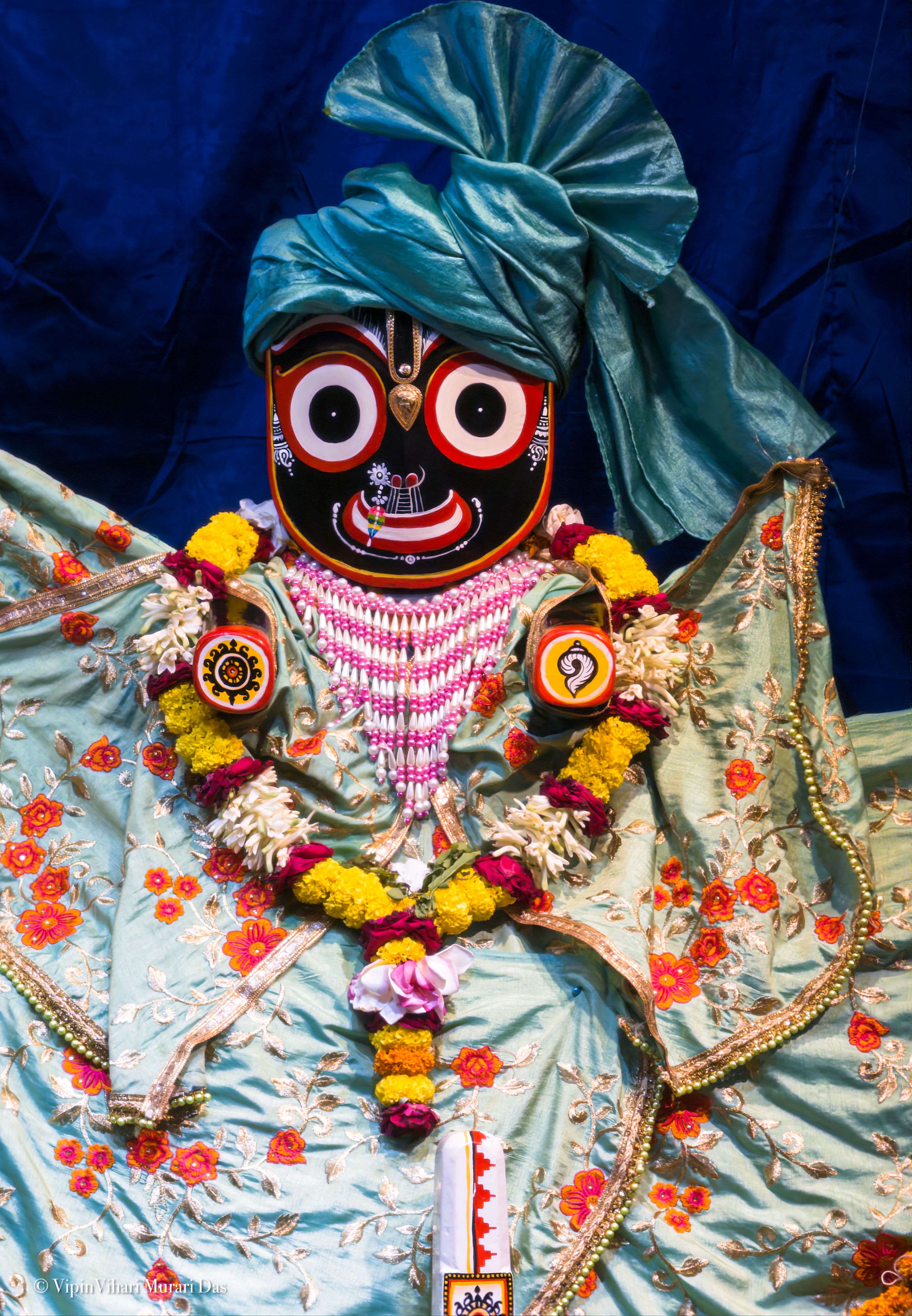 Intricately dressed Jagannath idol adorned with flowers and traditional garments, offering cultural significance.