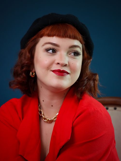 Free Portrait of a woman in red with vintage flair, beret, and bold jewelry. Stock Photo