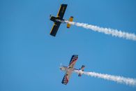 Two stunt planes perform aerobatic maneuvers against a clear blue sky in Chile.