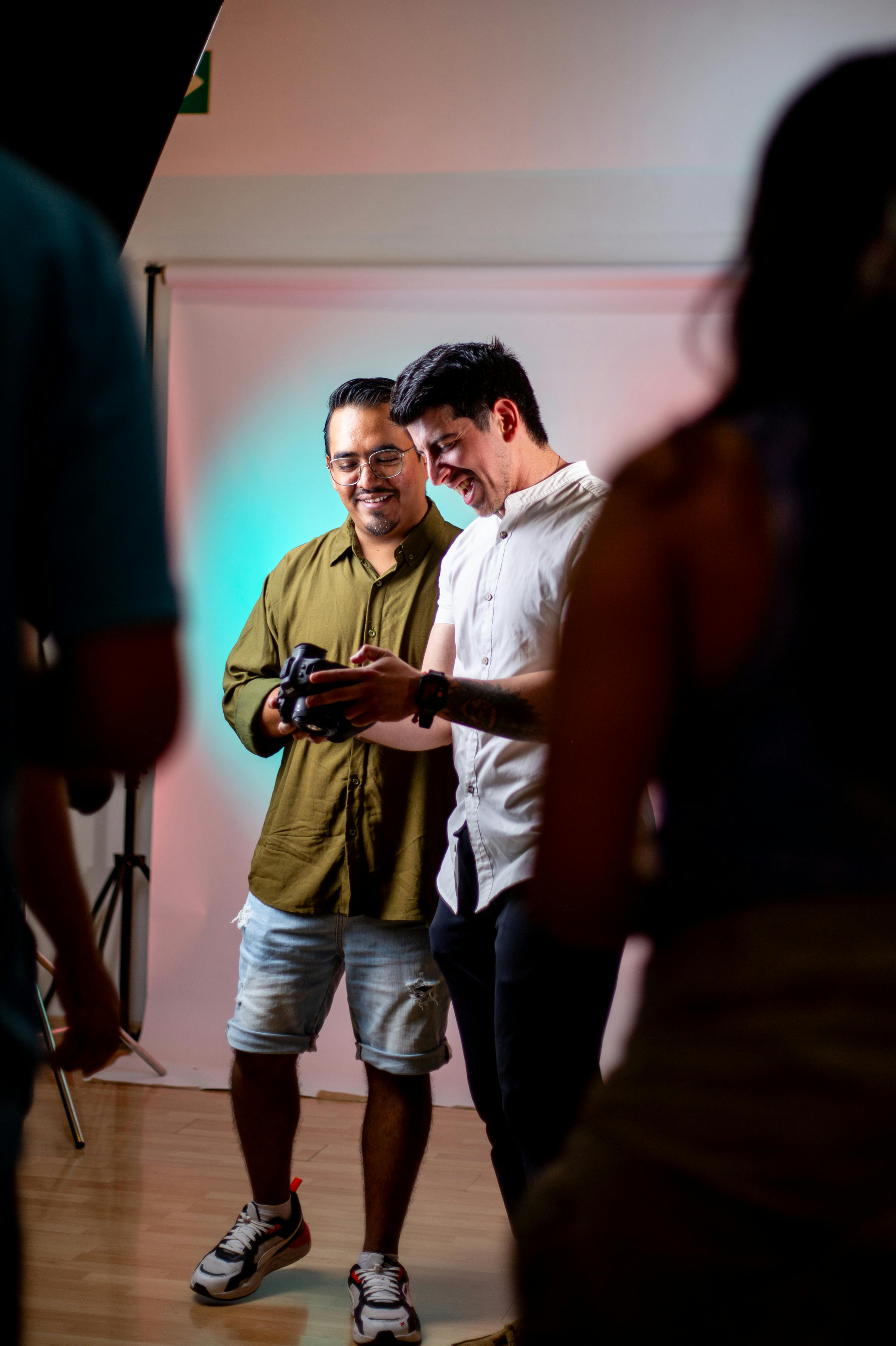 Two men discussing photos in a brightly lit studio setting.