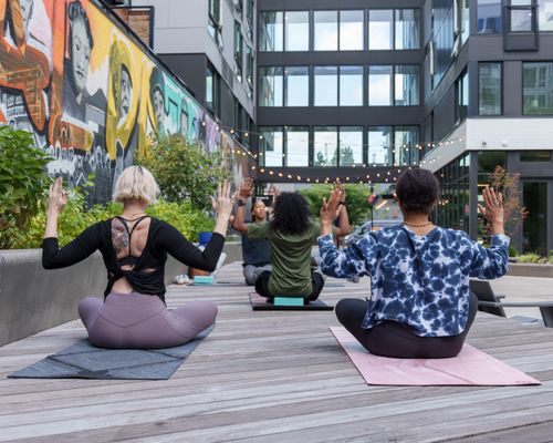 Free A diverse group of adults practicing yoga outdoors in a vibrant urban setting. Stock Photo