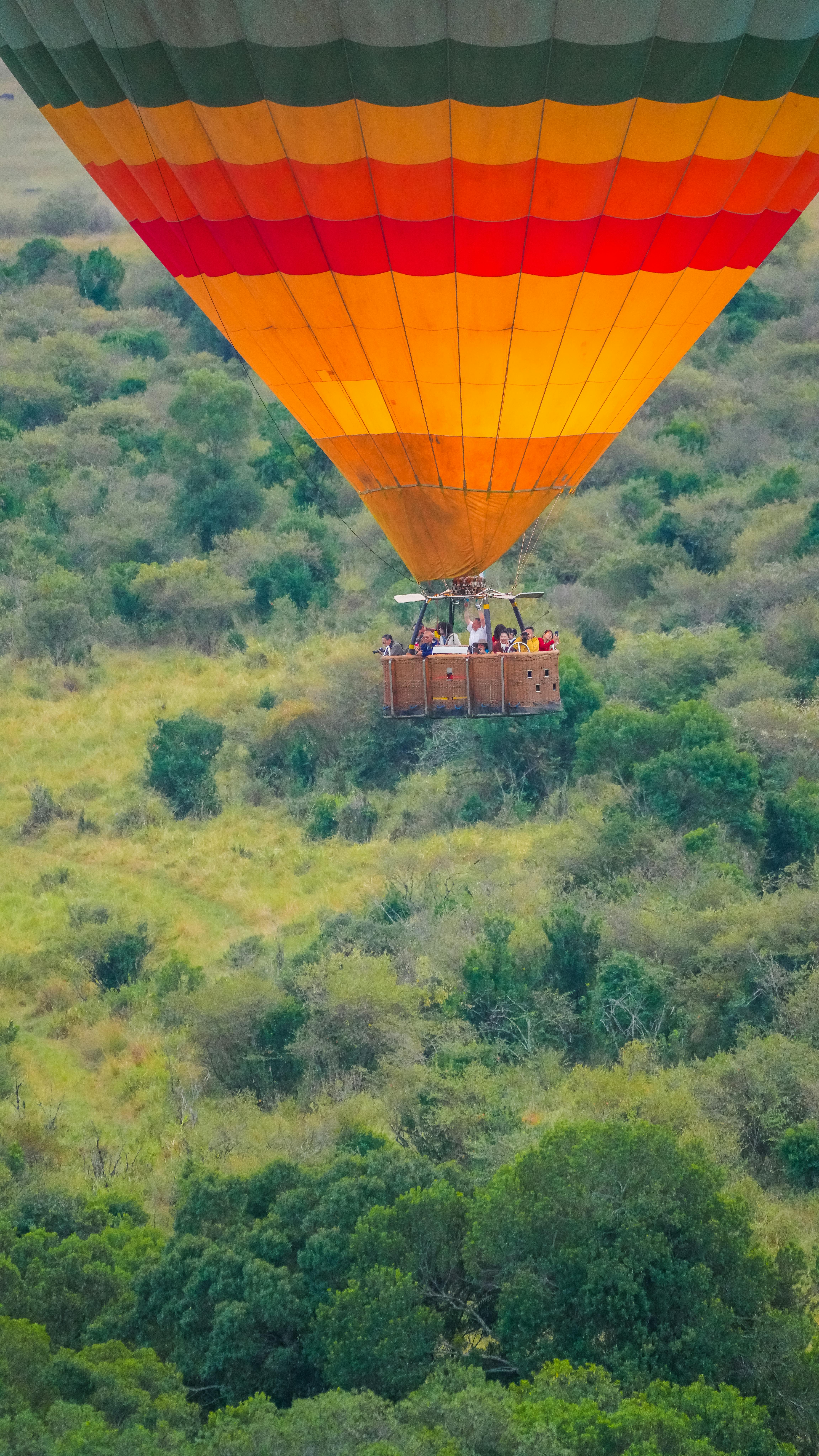 Capture of a vibrant hot air balloon gliding over lush landscapes in Kenya's rich savanna.