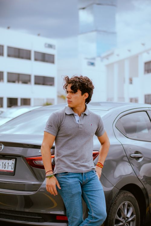 Free Stylish young man leaning on a car, in a modern urban setting. Vibrant, trendy, and confident vibe. Stock Photo