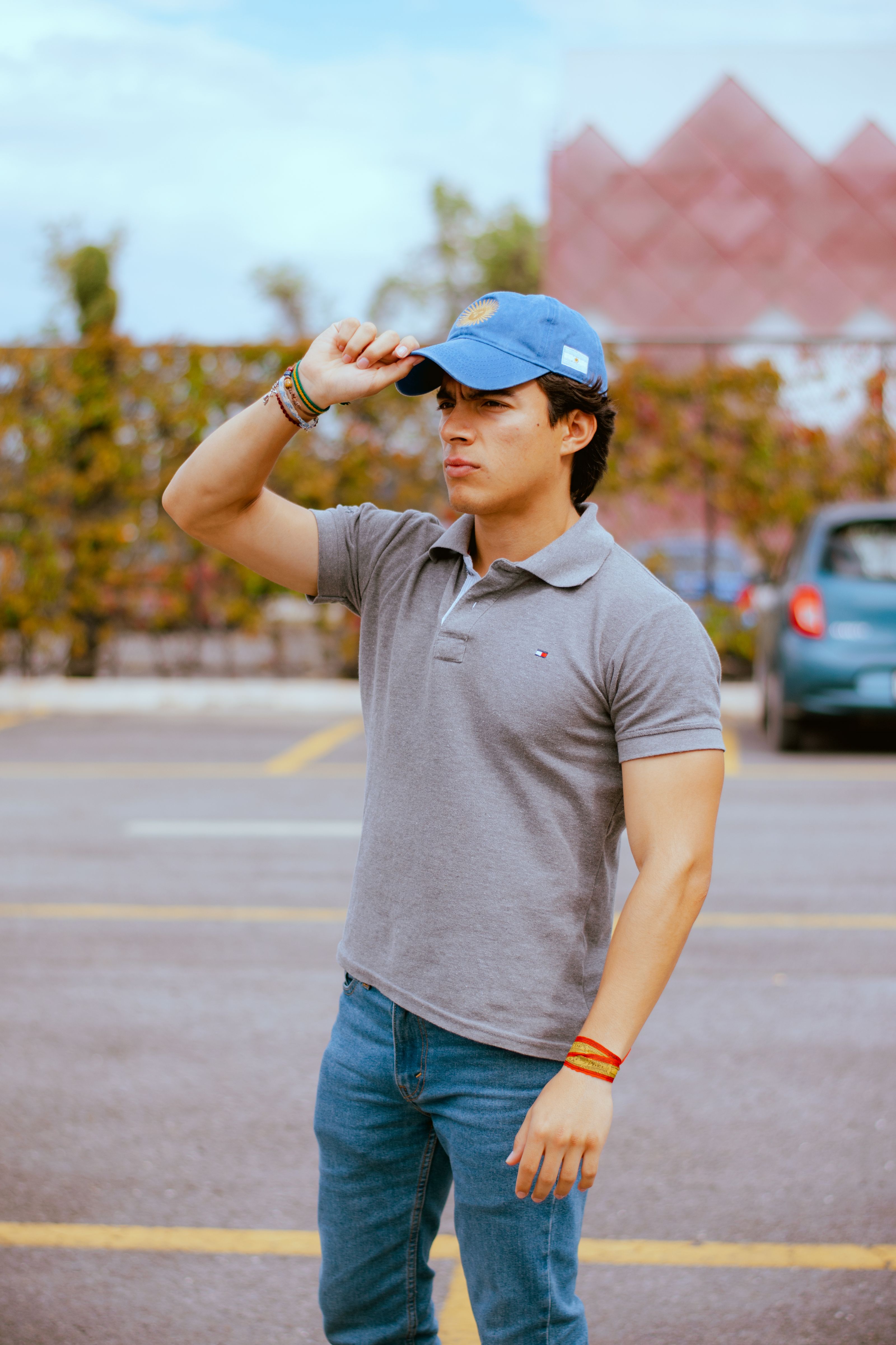 Jovem em roupa casual e boné em pé ao ar livre, transmitindo confiança.