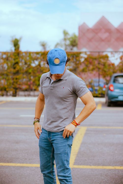 Free Young adult in casual streetwear outdoors, wearing a cap and jeans. Stock Photo