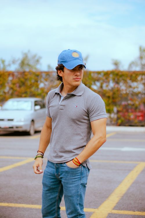 Free Man wearing a gray polo and blue jeans, standing confidently in a parking lot. Stock Photo