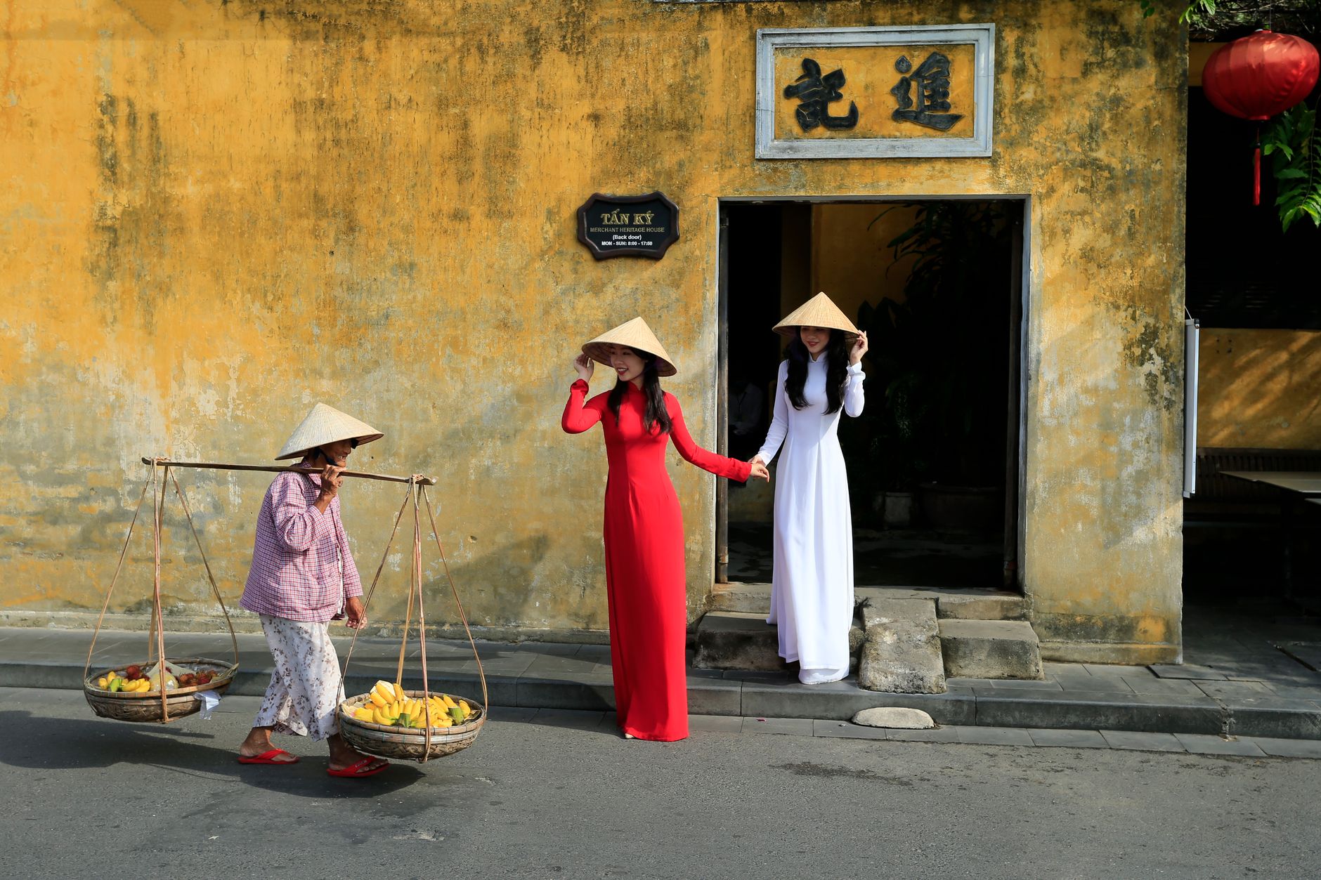 Women in conical hats in front of the historic Tân Ký house in Hoi An, Vietnam.